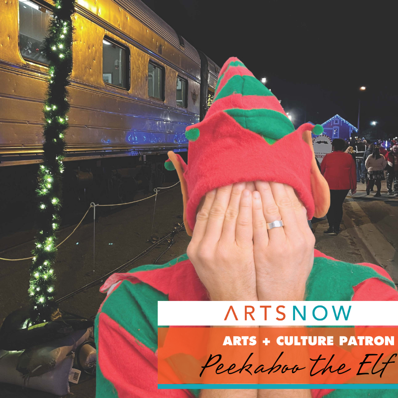 Photo of someone dressed as elf covering their face with their hands. To the right, is text in a white box with orange and blue text that reads: ArtsNow. Below is an orange box with white and black text that reads: Arts + Culture Patron: Peekaboo the Elf. A blue box is below this orange box.